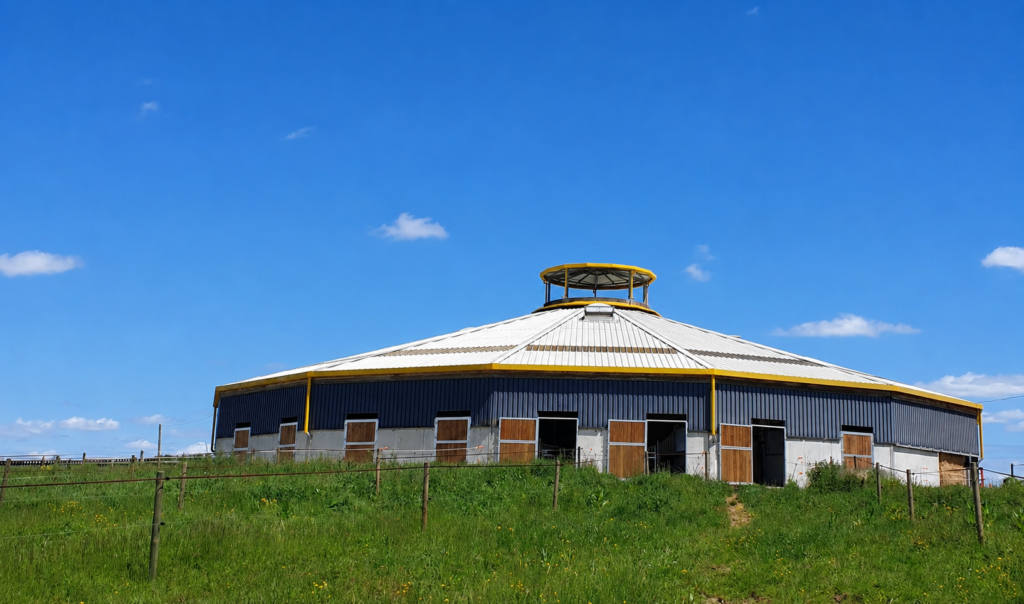 Bâtiment principal des Écuries d'Eurofarm à Confrançon dans l'Ain avec boxes pour chevaux et pâtures au premier plan.